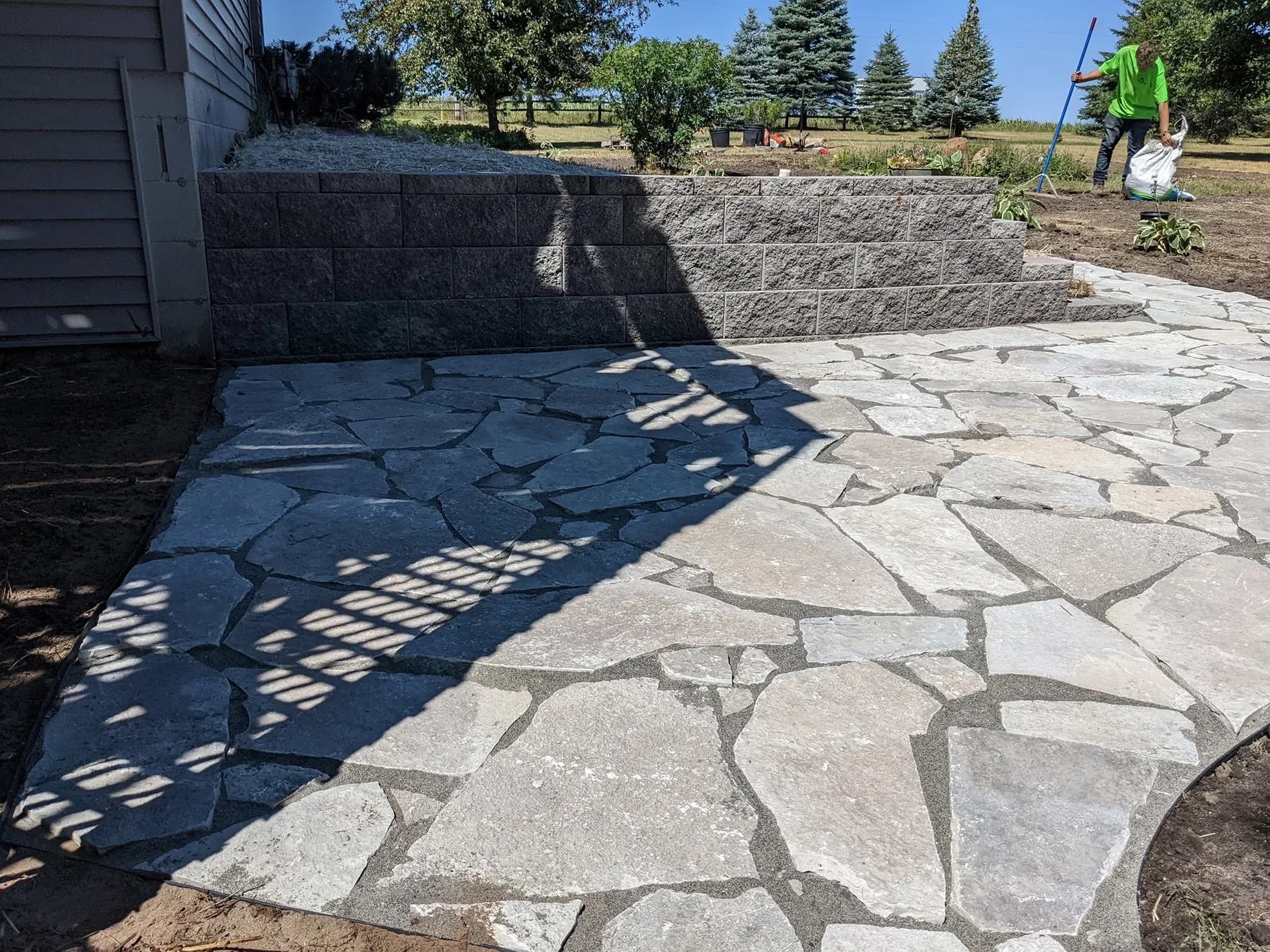 Natural stone patio beside a landscaped retaining wall